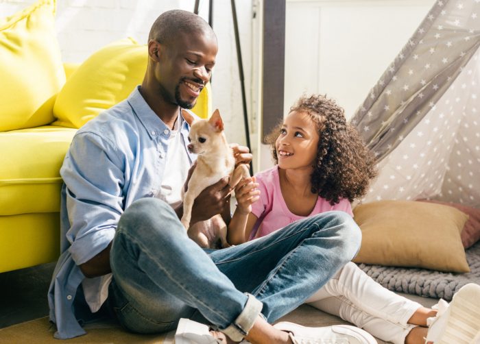 african american man holding a chihuahua sitting next to girl