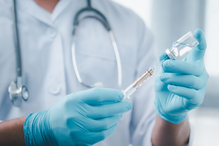 medical professional preparing a vaccine with a needle and syringe